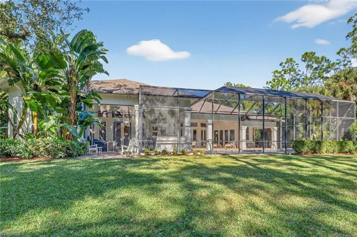 Back of property featuring a patio area, a yard, a lanai, a sunroom, and ceiling fan