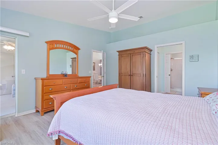Bedroom with ensuite bathroom, light wood-type flooring, and ceiling fan