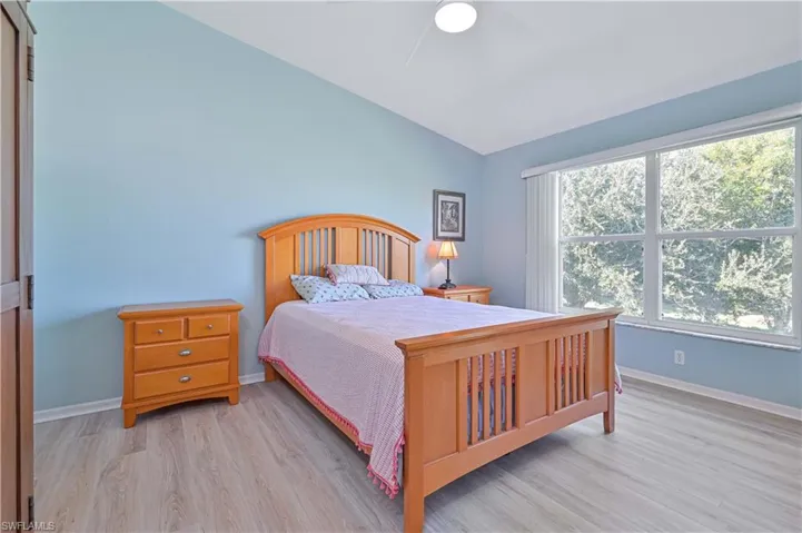 Bedroom with light wood-type flooring, a ceiling fan, and vaulted ceiling