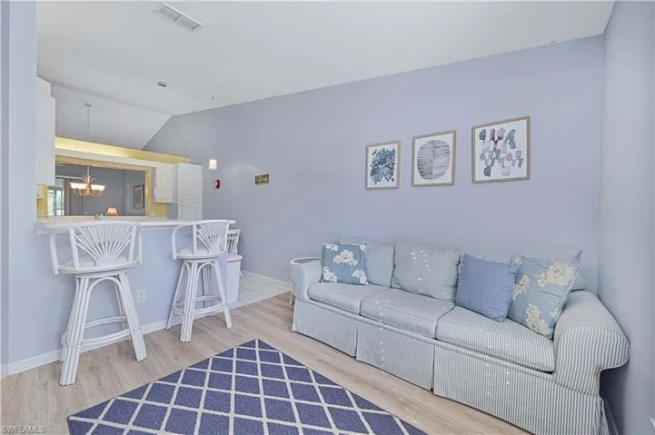 Living area with light wood-style floors, lofted ceiling, and hanging lights