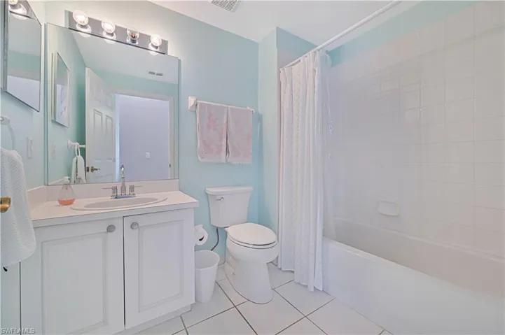 Bathroom with vanity, shower / tub combo with curtain, and light tile patterned flooring