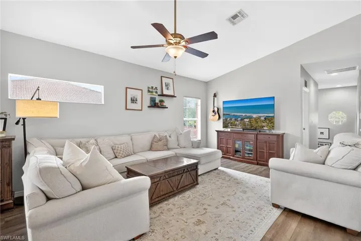 Spacious living area featuring wood-finish flooring, a ceiling fan, and recessed lighting