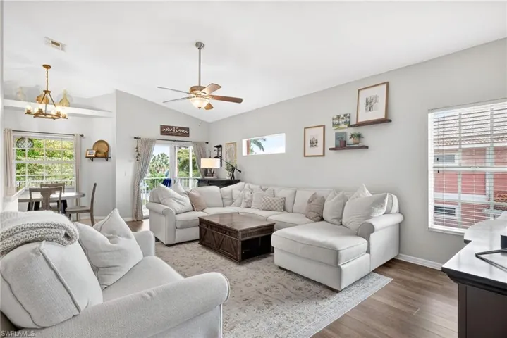 Spacious living area featuring vaulted ceilings, wood-finish flooring, and a ceiling fan