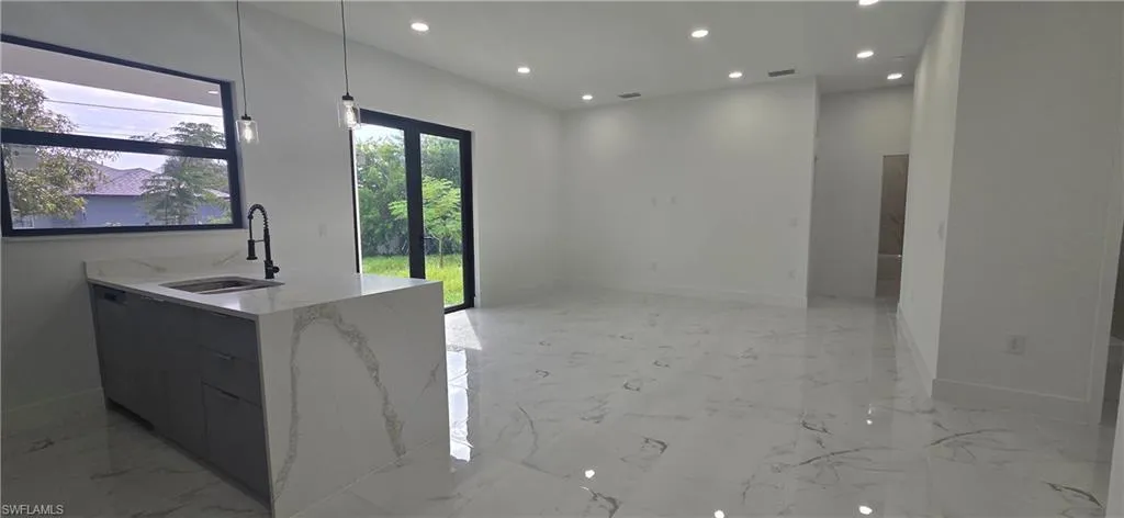 Kitchen with light marble finish floors, hanging light fixtures, light stone countertops, and recessed lighting