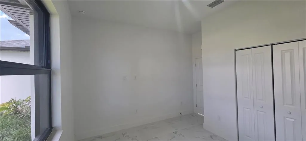 Unfurnished bedroom featuring light marble finish floors and a closet