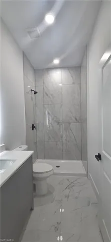 Bathroom with a marble finish shower, vanity, and light marble finish floors