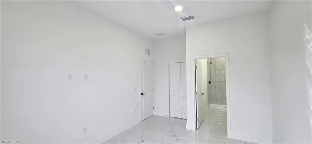 Unfurnished bedroom featuring light marble finish floors, ensuite bathroom, and a closet
