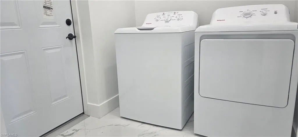 Laundry room featuring light marble finish flooring and washer and dryer