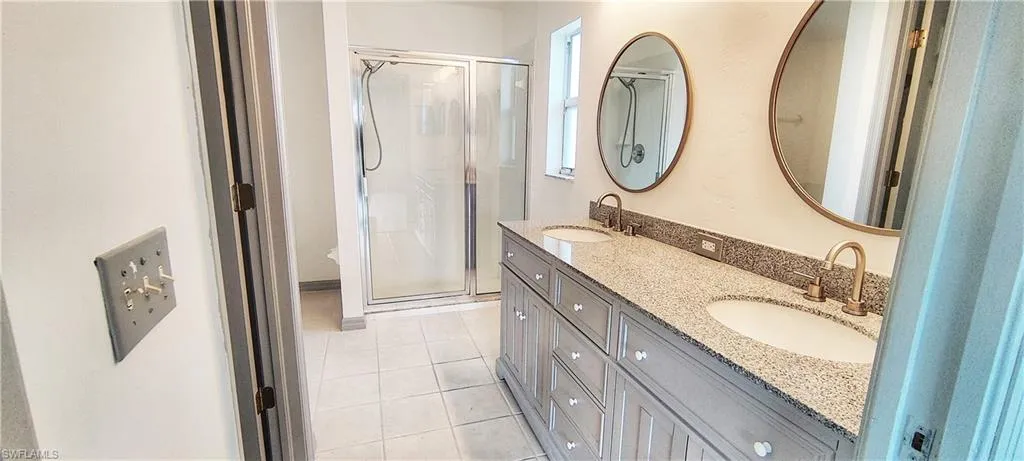 Bathroom with vanity, a shower with door, and tile patterned flooring