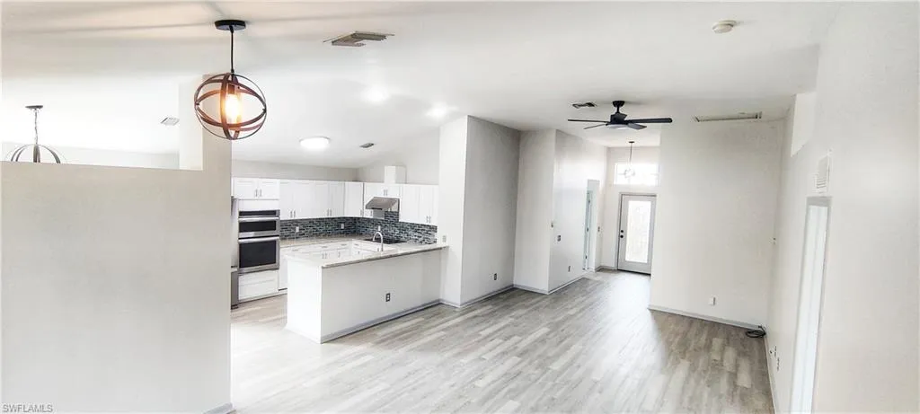 Kitchen with tasteful backsplash, white cabinetry, sink, a high ceiling, and kitchen peninsula