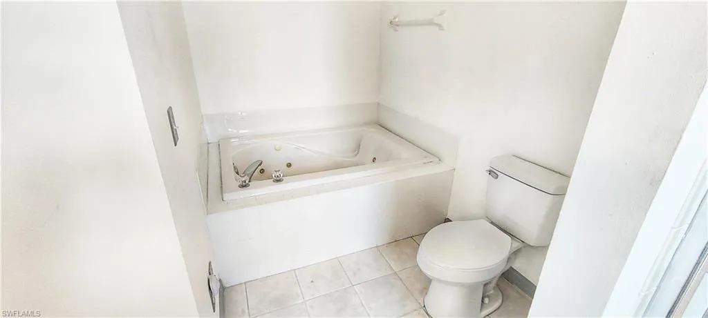 Bathroom featuring tiled bath, tile patterned floors, and toilet