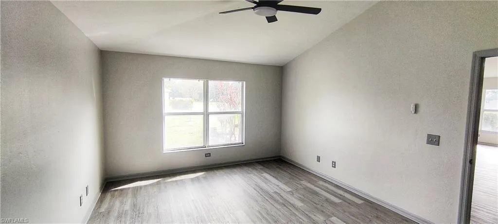 Empty room featuring ceiling fan, lofted ceiling, and light wood-type flooring