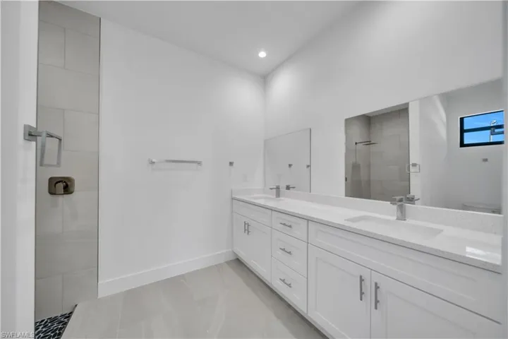 Full bathroom with a walk in shower, double vanity, and recessed lighting