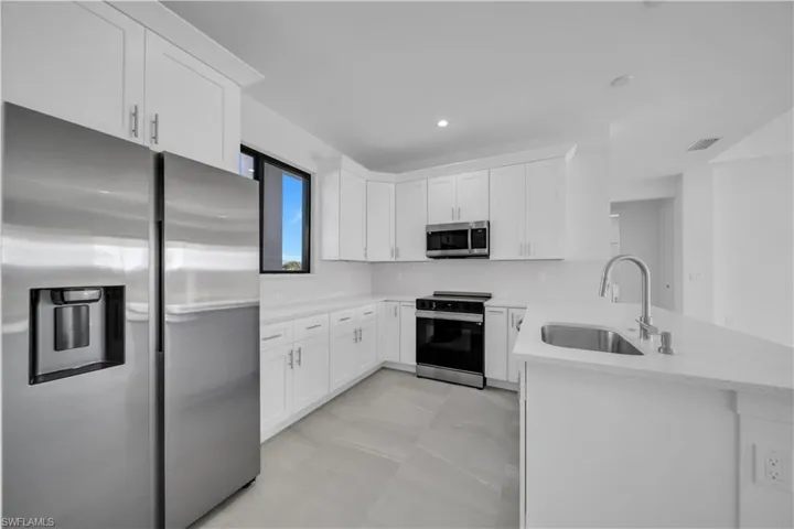 Kitchen featuring appliances with stainless steel finishes, white cabinetry, a peninsula, and recessed lighting