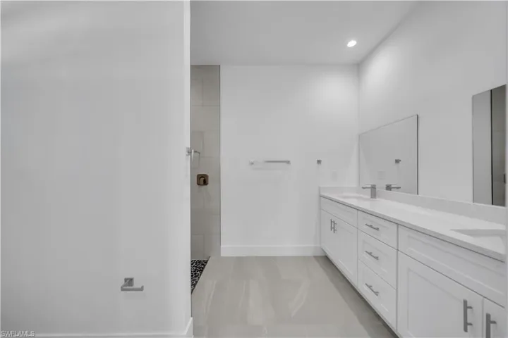 Bathroom featuring double vanity, walk in shower, and recessed lighting