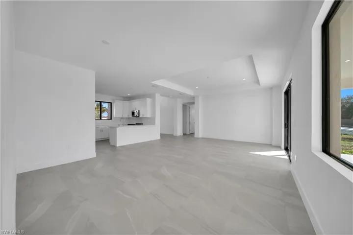 Unfurnished living room featuring a tray ceiling and recessed lighting