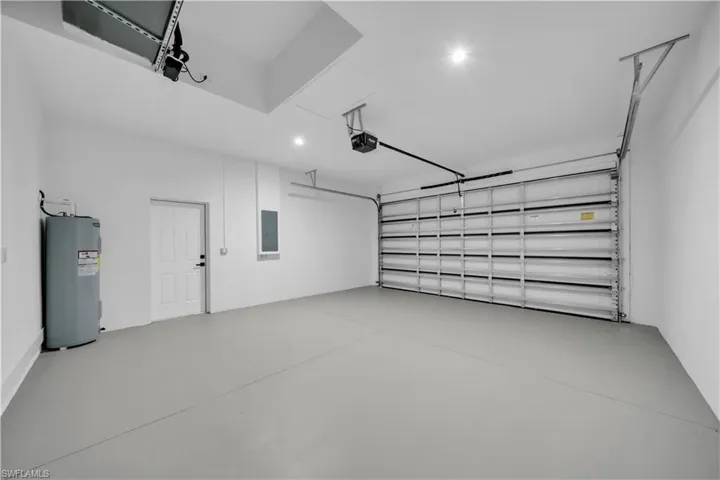 Garage with water heater, electric panel, and recessed lighting
