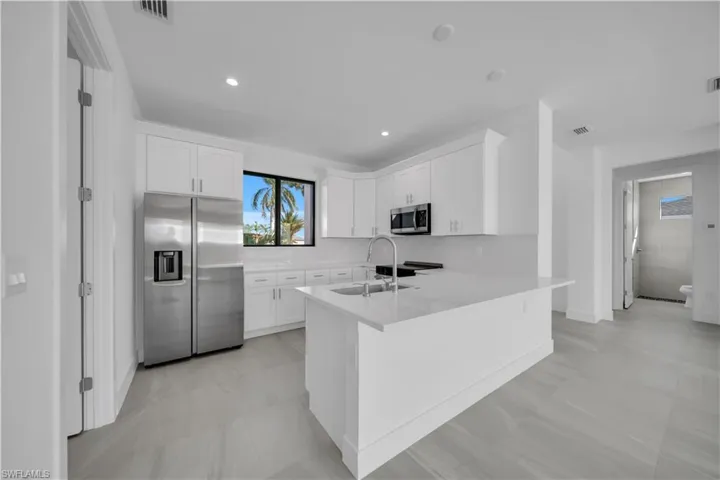 Kitchen featuring stainless steel appliances, white cabinetry, light stone counters, a peninsula, and recessed lighting