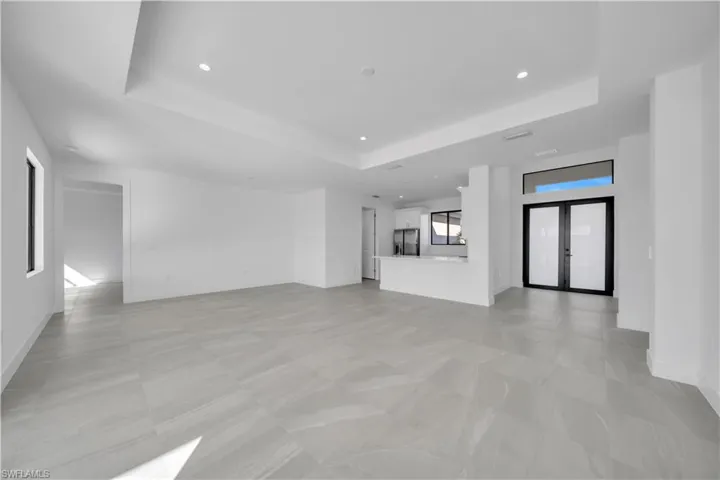Unfurnished living room with a raised ceiling, french doors, and recessed lighting