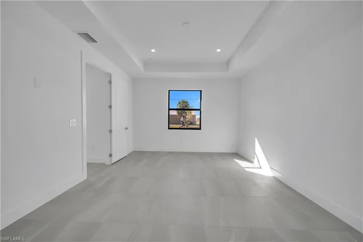 Empty room featuring a tray ceiling and recessed lighting
