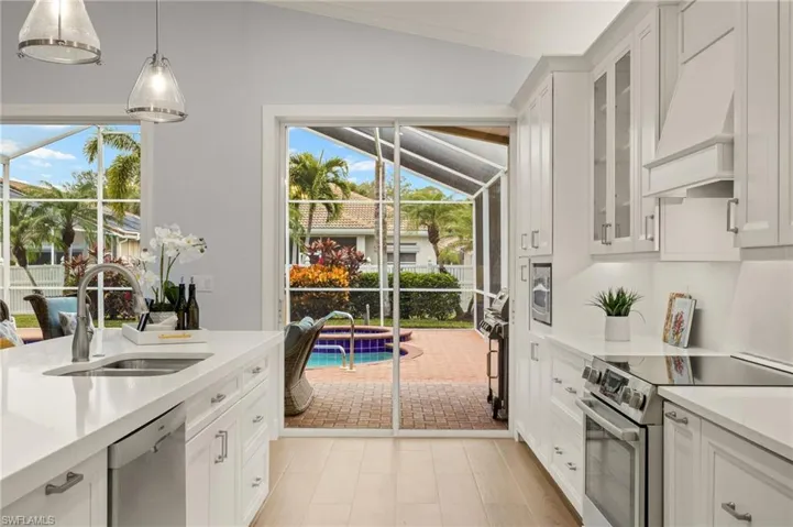 Kitchen featuring stainless steel appliances, lofted ceiling, white cabinets, and sink