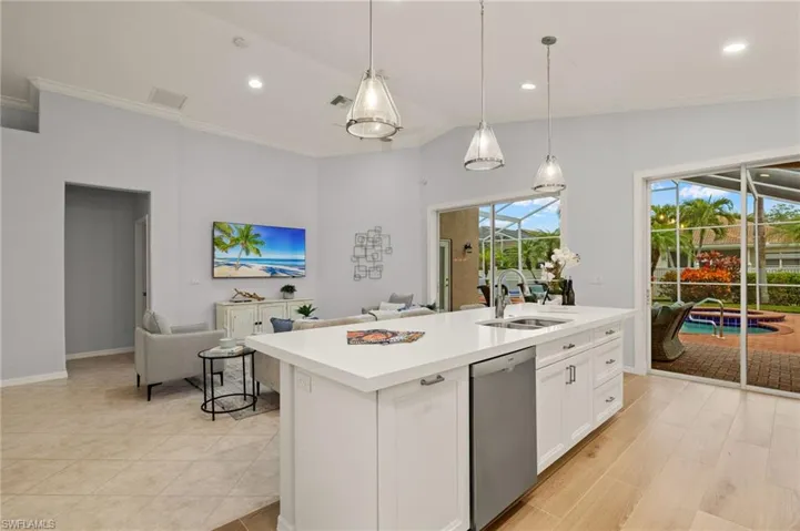 Kitchen with sink, hanging light fixtures, dishwasher, and an island with sink
