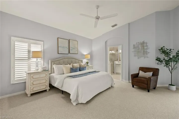 Carpeted bedroom featuring ceiling fan, vaulted ceiling, and connected bathroom