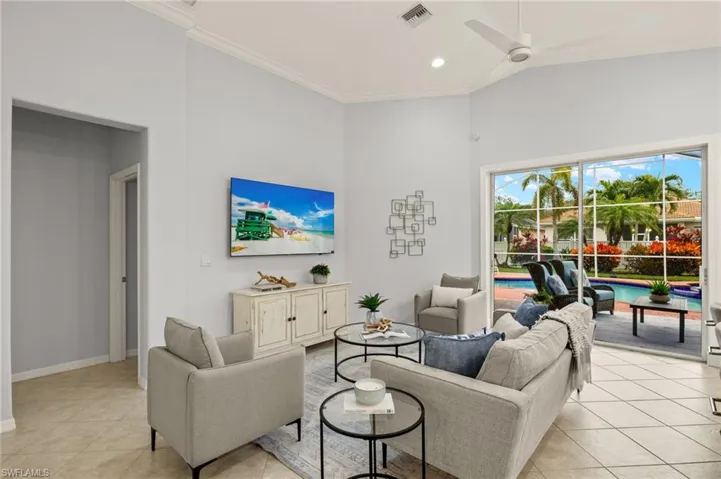 Living room with ceiling fan, light tile patterned floors, and crown molding