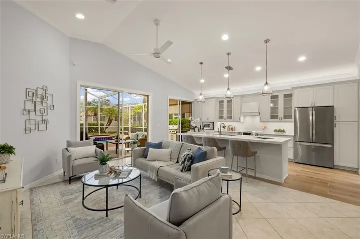Tiled living room with vaulted ceiling, ceiling fan, crown molding, and sink