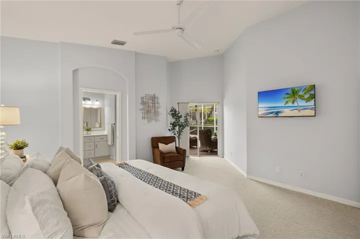 Carpeted bedroom with ensuite bathroom and ceiling fan