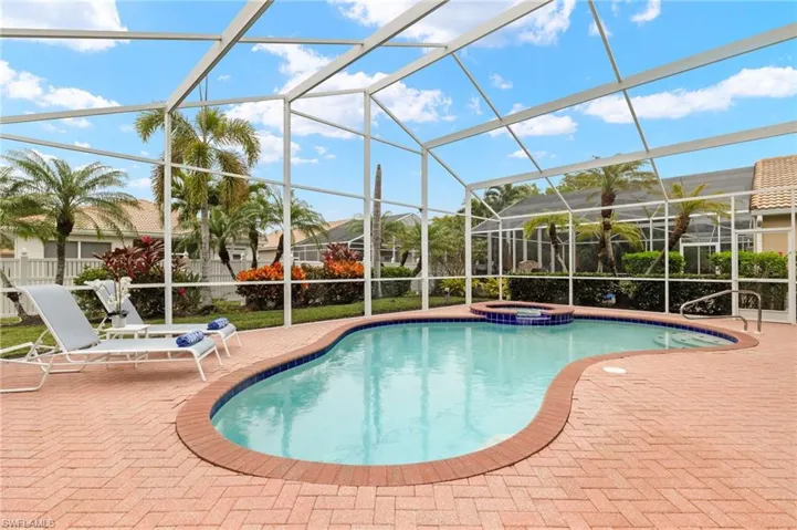 View of swimming pool with glass enclosure, a patio area, and an in ground hot tub