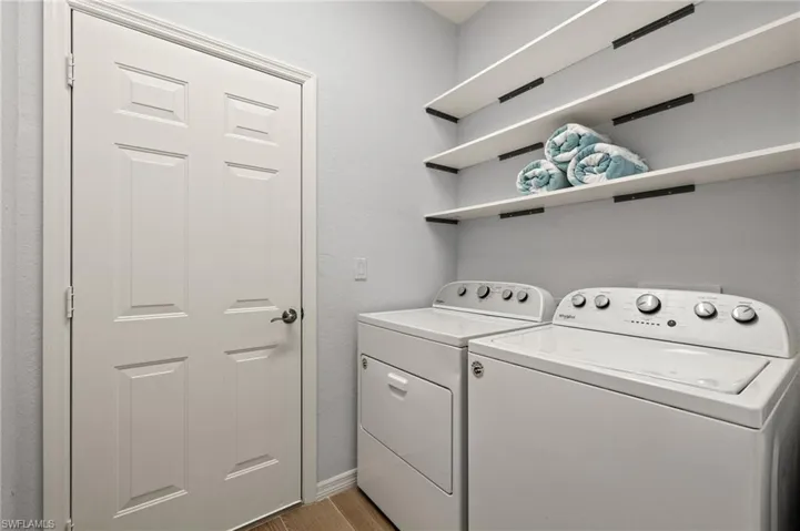 Clothes washing area with washer and dryer and light hardwood / wood-style floors