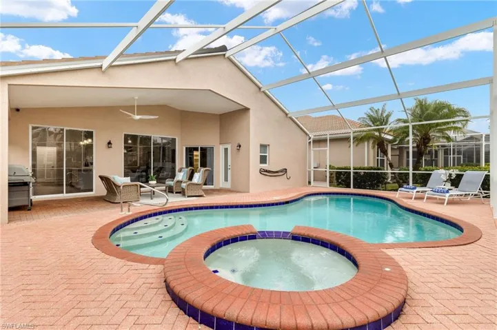 View of swimming pool with an in ground hot tub, a lanai, a grill, and a patio