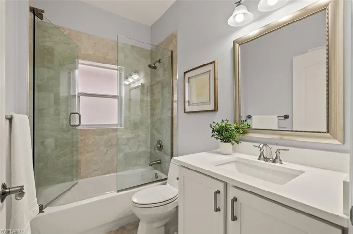 Full bathroom featuring enclosed tub / shower combo, vanity, and toilet