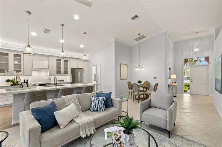 Living room with sink, a high ceiling, light tile patterned floors, and crown molding