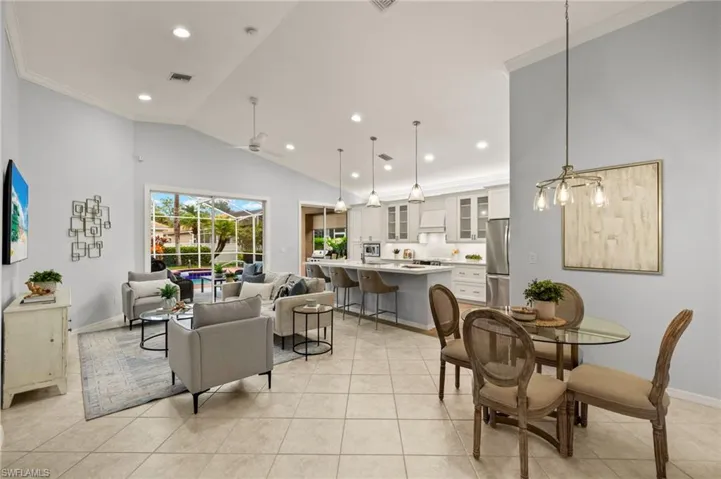 Dining area with ceiling fan, light tile patterned floors, vaulted ceiling, and crown molding