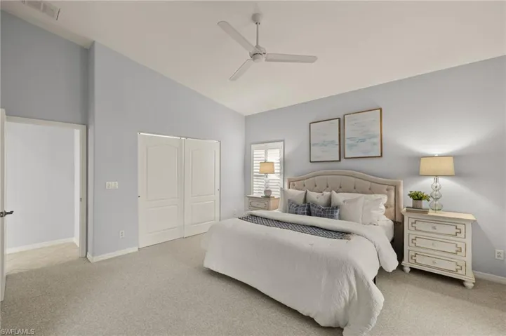 Carpeted bedroom featuring ceiling fan, high vaulted ceiling, and a closet