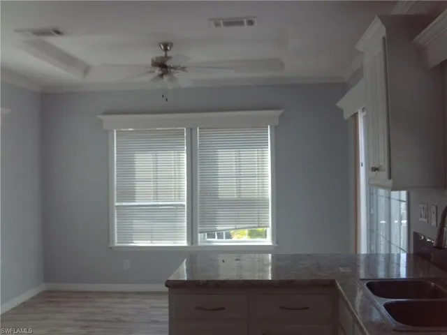 Kitchen featuring light wood-style floors, a raised ceiling, visible vents, and a sink