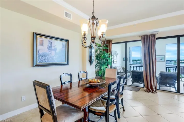 Dining area with light tile patterned floors, crown molding, and a chandelier