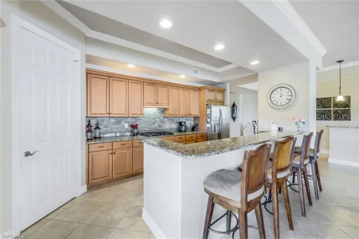 Kitchen with large walk in pantry, stainless steel appliances, a breakfast bar area, tasteful backsplash, hanging light fixtures, and light stone countertops
