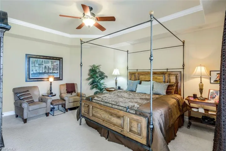 Master Suite with king bed, tray ceiling, crown molding, and ceiling fan and screened private lanai access.