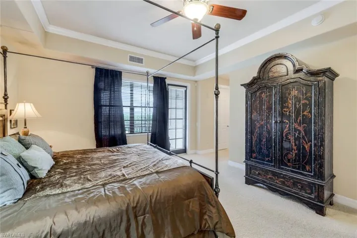 Primary bedroom featuring a raised ceiling, crown molding, and ceiling fan
