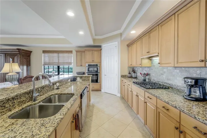 Kitchen featuring appliances with stainless steel finishes, sink, light stone countertops, and a tray ceiling