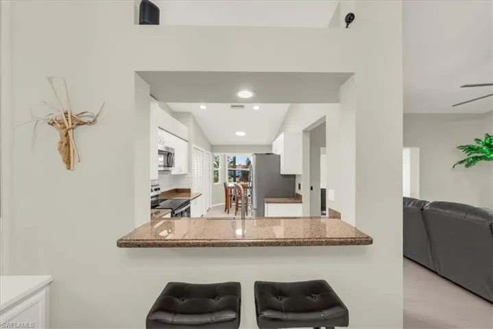 Kitchen featuring white cabinets, stainless steel appliances, recessed lighting, open floor plan, and a kitchen breakfast bar