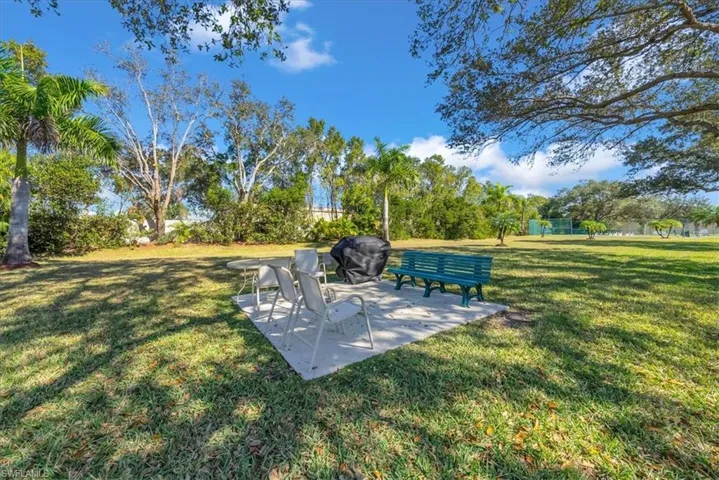 View of green lawn featuring a patio area and view of scattered trees