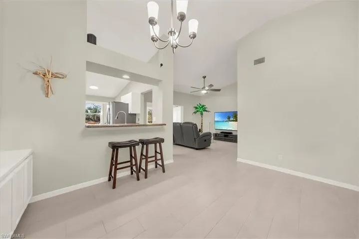 Dining area featuring a chandelier, high vaulted ceiling, light wood finished floors, and ceiling fan