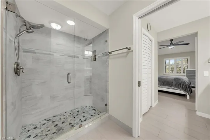 Ensuite bathroom featuring a shower stall and a ceiling fan