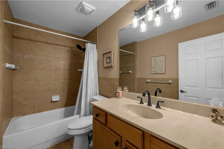 Bathroom featuring vanity, shower / bath combo with shower curtain, tile walls, and tile patterned flooring