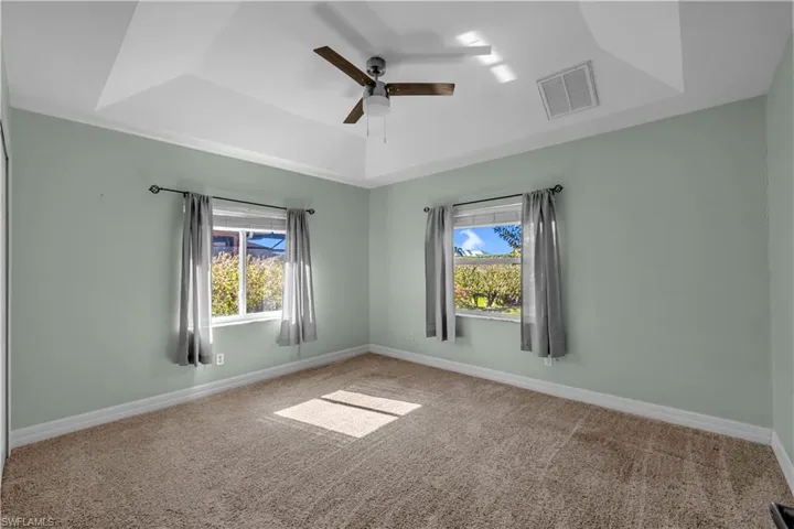 Spare room with a tray ceiling, carpet, and ceiling fan