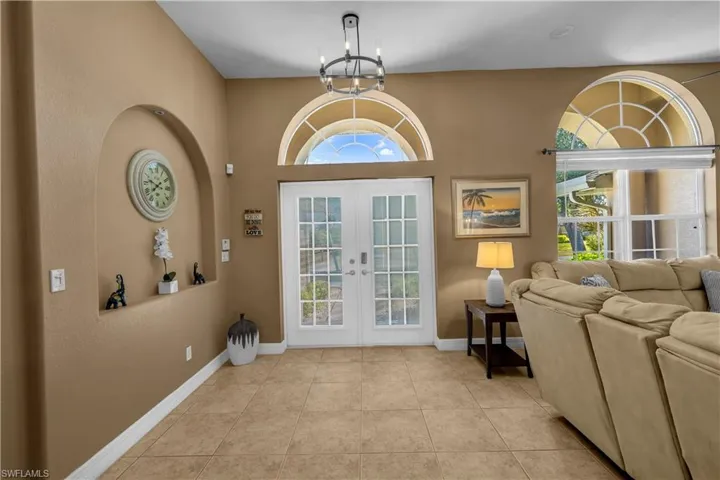 Foyer with french doors, hanging lights, light tile patterned flooring, and a textured wall